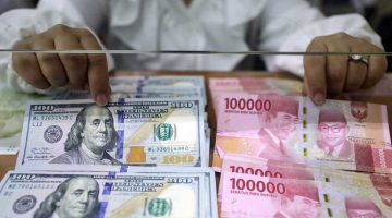 Pegawai menunjukan mata uang rupiah dan dolar Amerika Serikat di Dolar Asia Money Changer, Jakarta, Senin (18/7/2022). Bisnis/Himawan L Nugraha